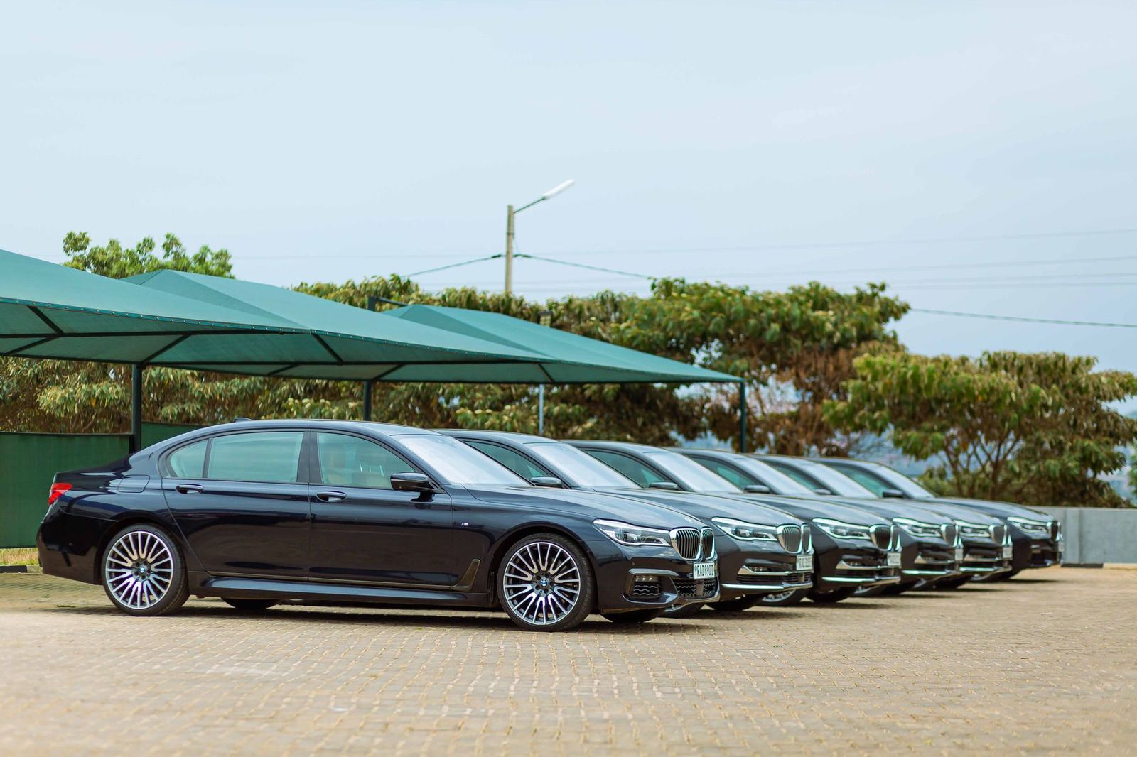 A row of black executive sedans parked under a canopy