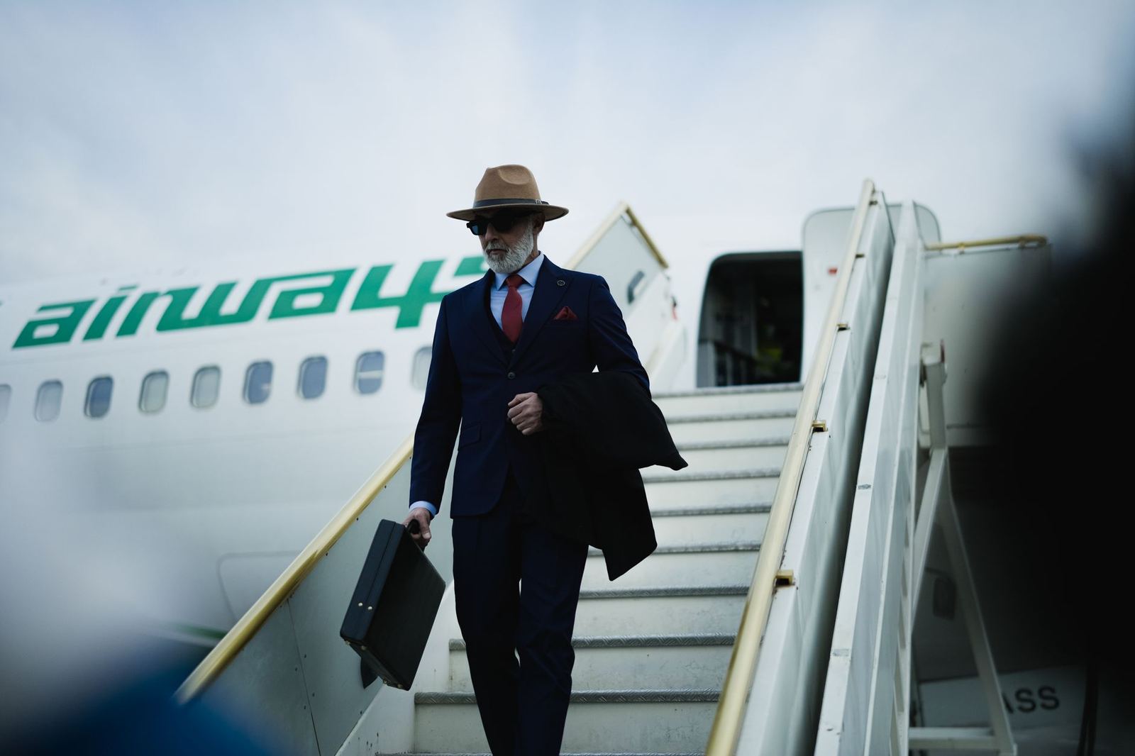 A passenger in a suit descending the airstairs of a private jet