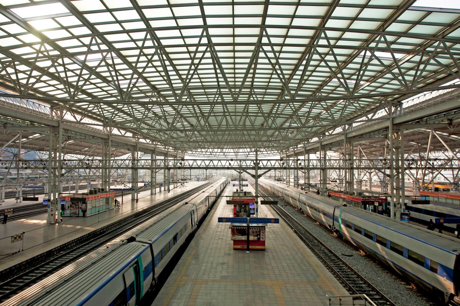 Trains waiting under the glass roof of a large railway station